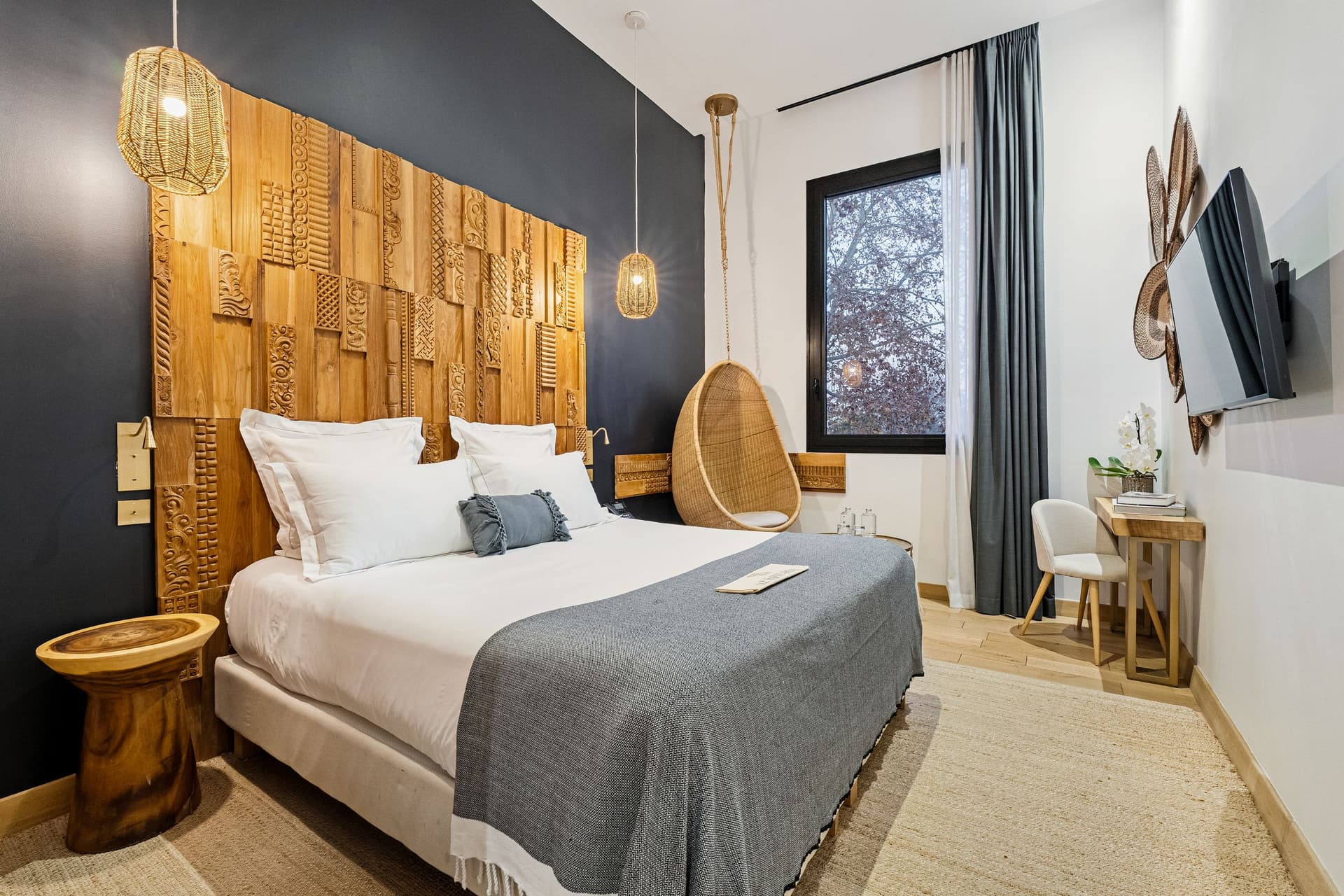 Chambre moderne avec lit, fauteuil suspendu, décoration bois.